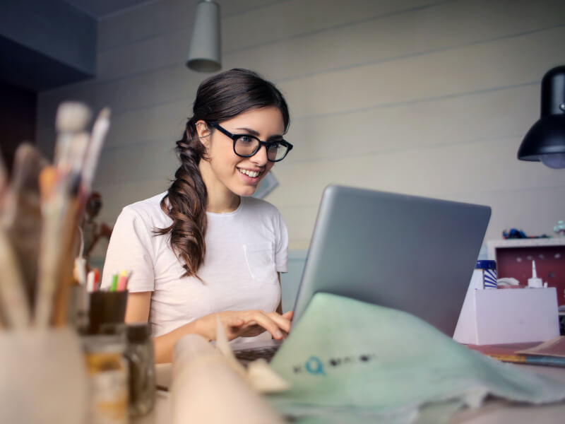 A person smiling whilst typing on a laptop
