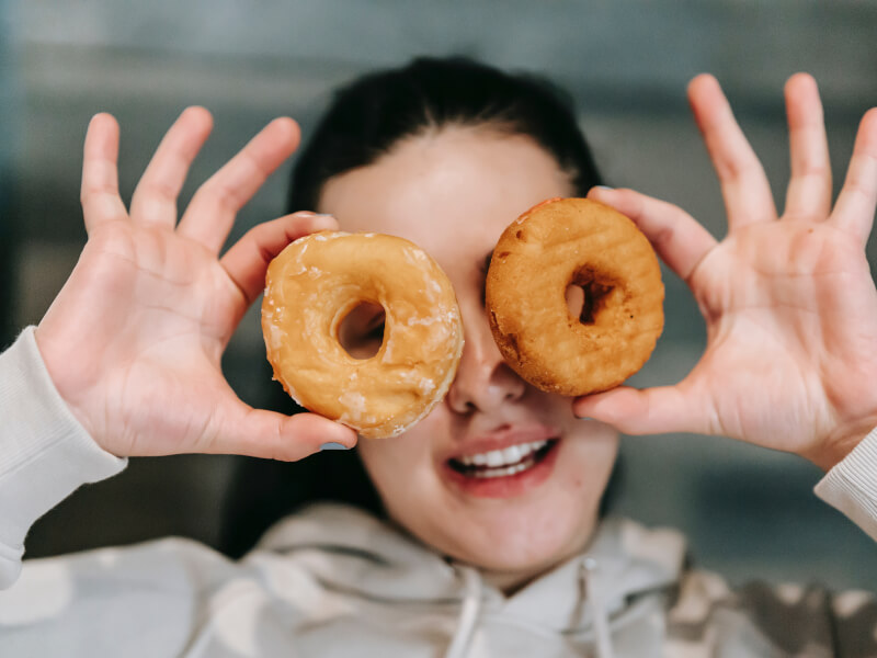 Someone holds up two doughnuts over their eyes.