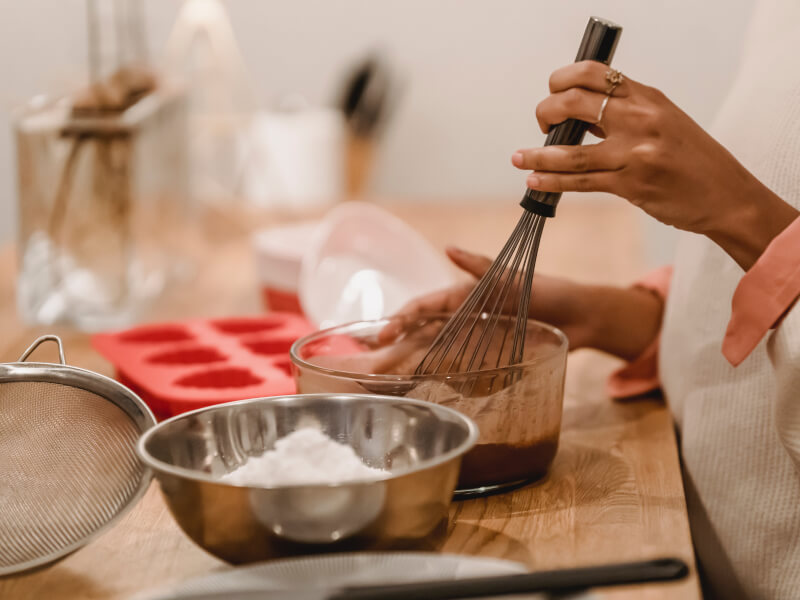 Woman holding whisk whilst making chocolate at home. 