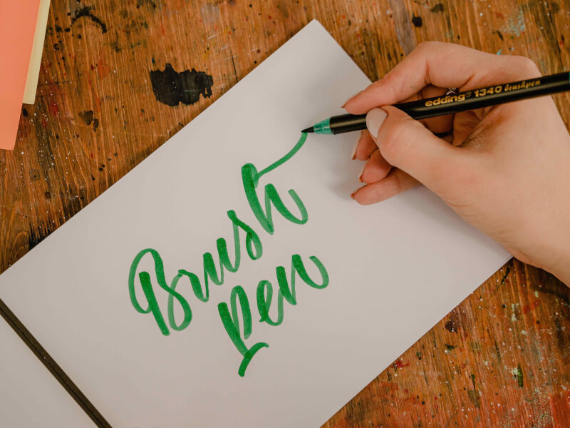 A person writing on paper using brush lettering