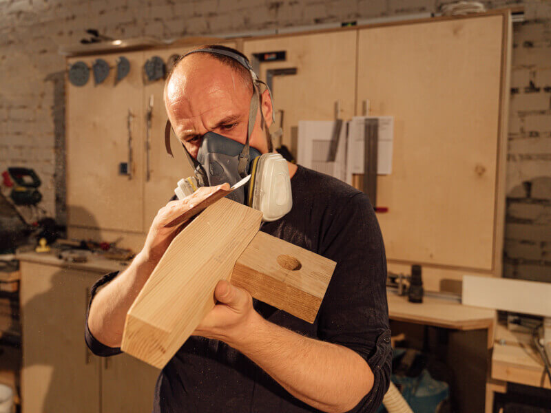 A man sands a woodworking project joint.