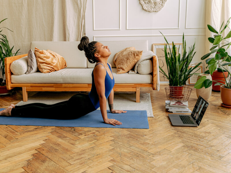 A woman doing an online yoga class at home.