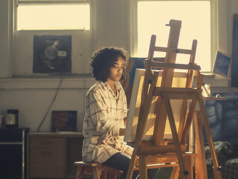 Woman sitting at an artist easel during a painting class in London.