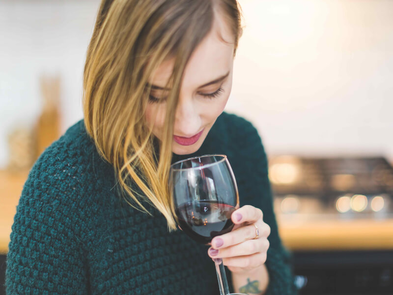 A person smelling a glass of red wine