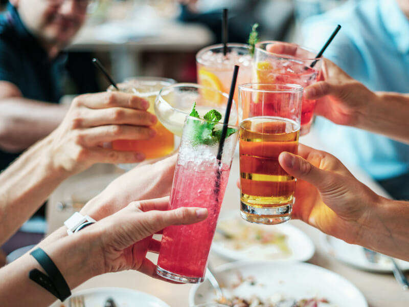 A group cheers a variety of drinks after cocktail making at home.