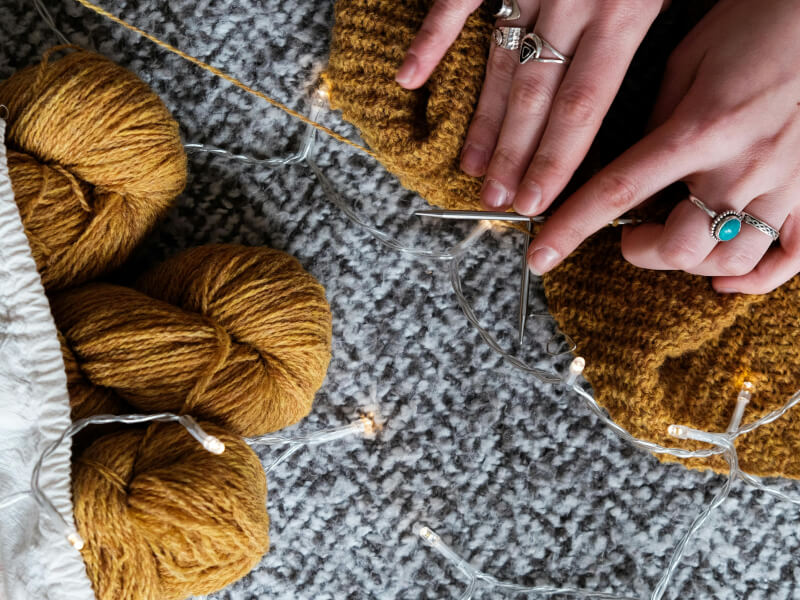 Overhead shot of a person knitting with ochre yarn
