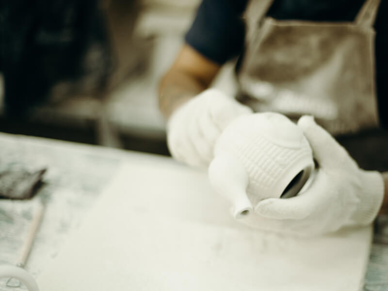 A person creating a glazed pottery teapot during a pottery class