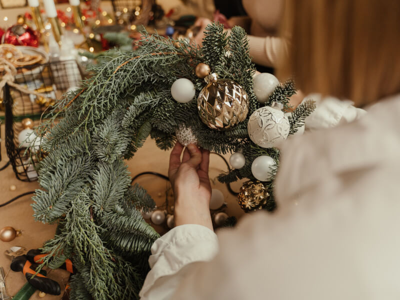 Person making a DIY Christmas Wreath at a wreath making workshop. 