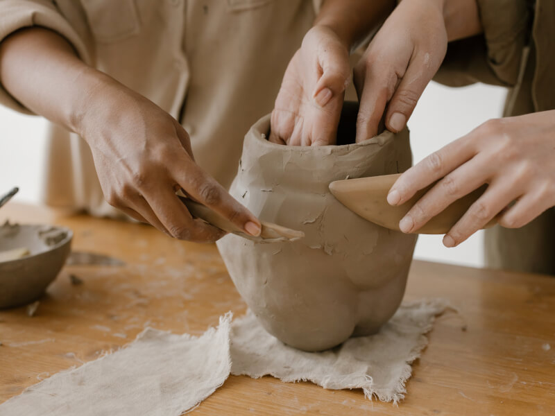 Two sets of hands sculpt clay as they make some DIY pottery.