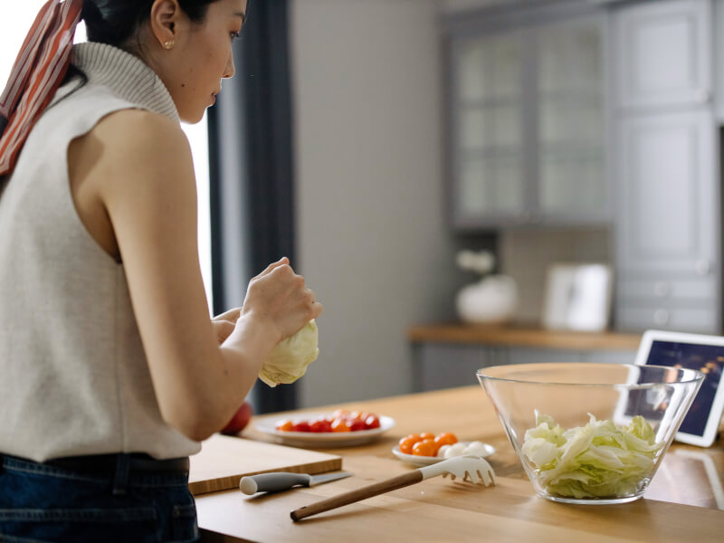 A woman is making a vegan meal in a kitchen with a tablet in front of her