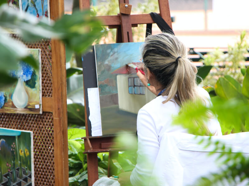 A woman paints a house in an art class.