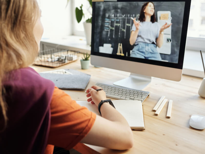 A person sits at their desk and takes part in an online class
