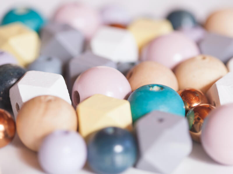 Various wooden circular and geometric beads for selection in a jewellery making class.