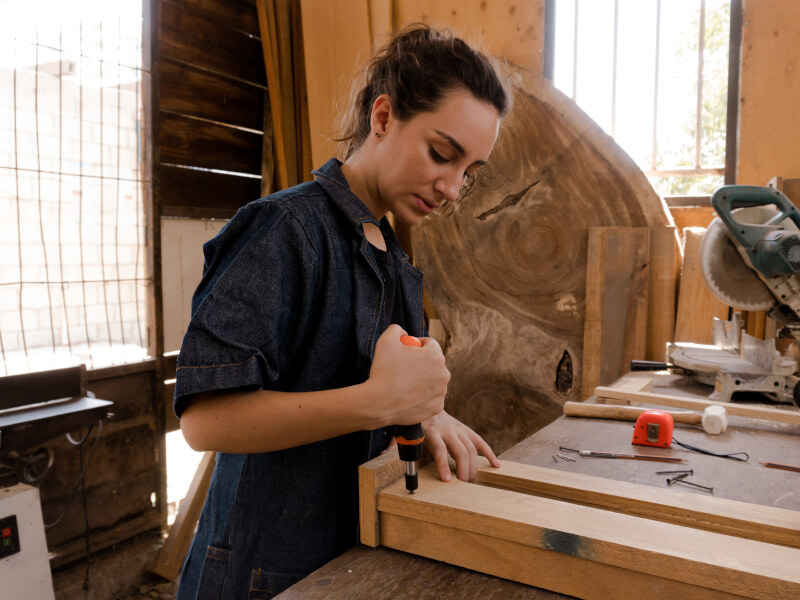A woman is working on a project in a woodworking workshop.