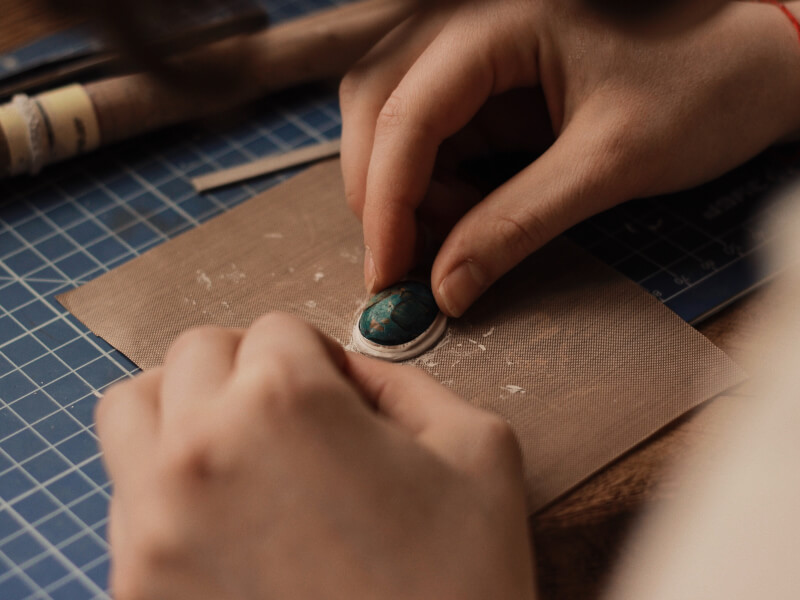 A pendant with green stone being sanded down.