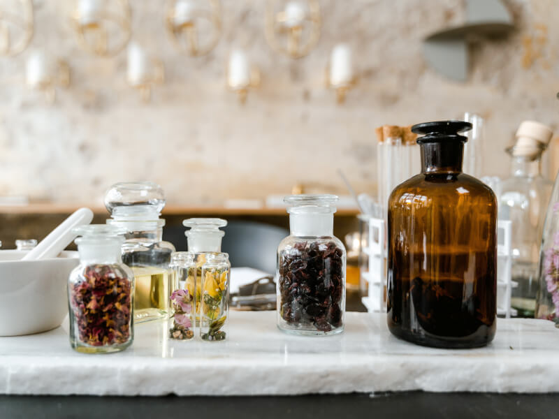 A selection of dried flowers in jars next to a white pestle and mortar
