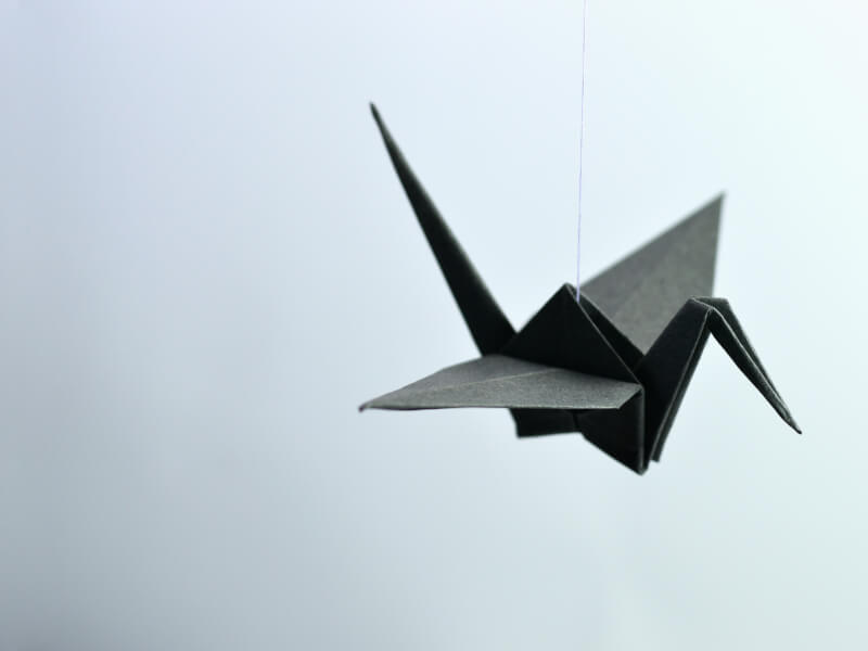 Floating paper origami on a string in the shape of a bird.