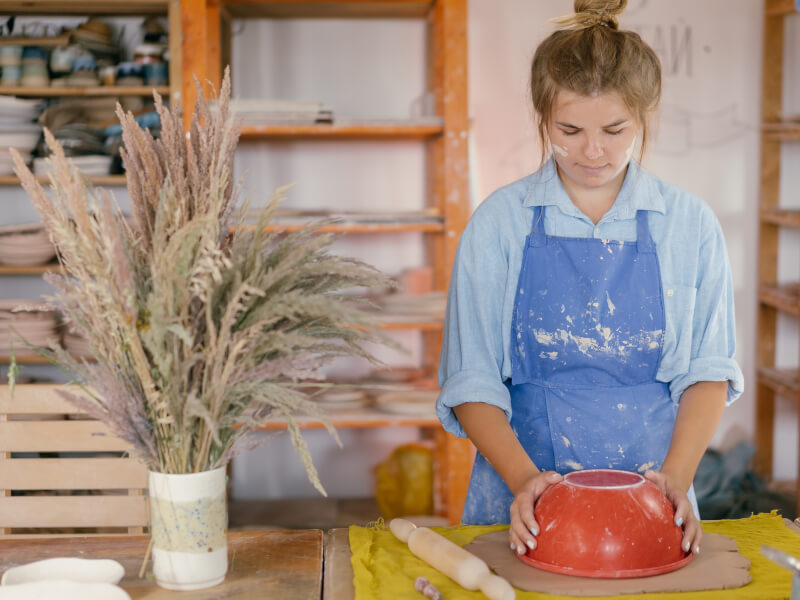 Woman wearing blue apron and shirt at a pottery making class.