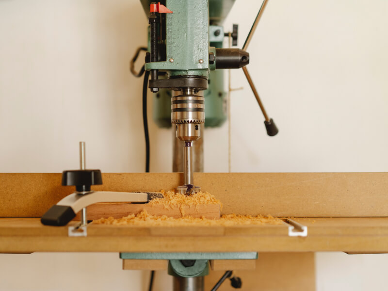 A mechanical woodworking tool drills into timber.