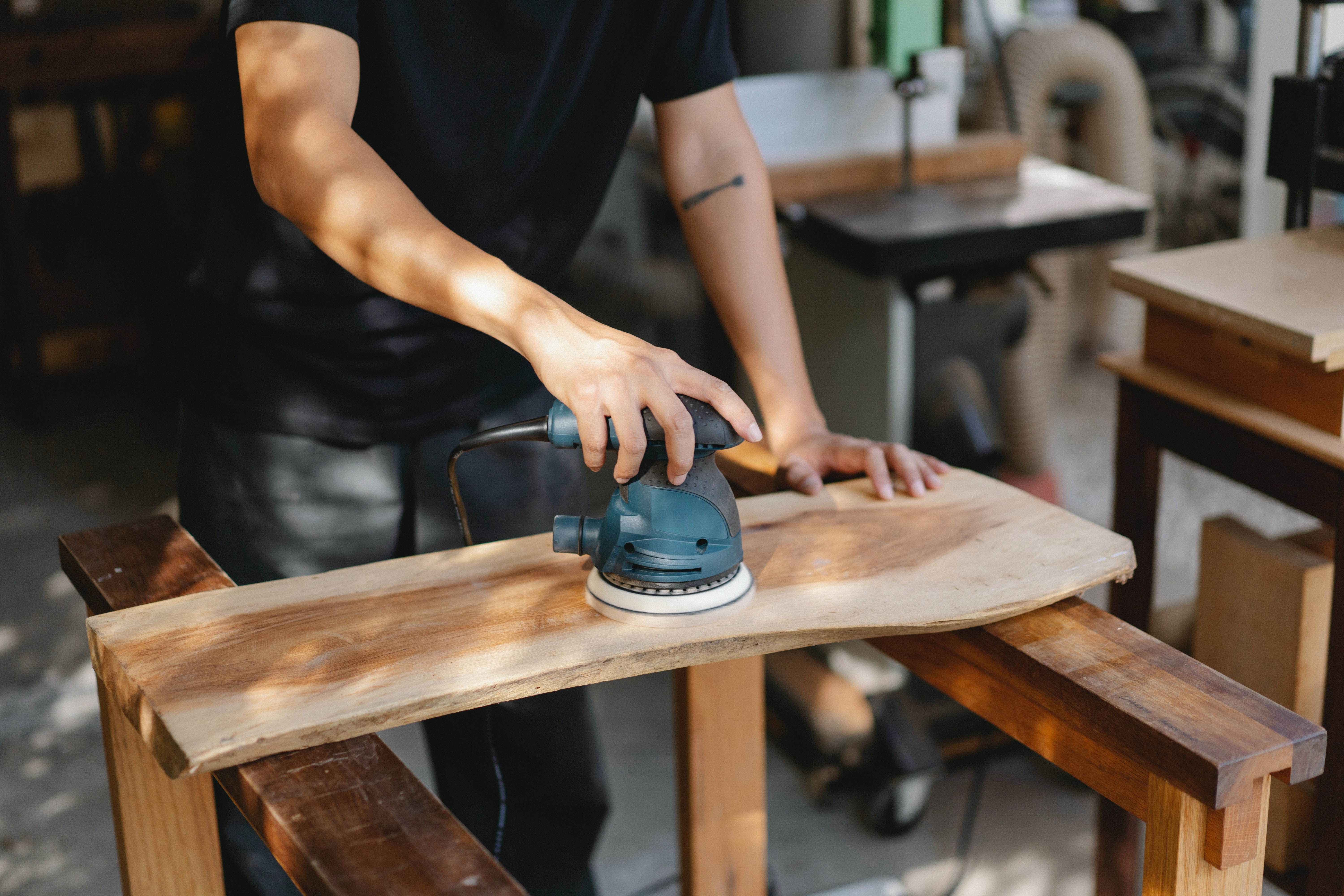 A person is sanding down a piece of wood for a woodworking project.
