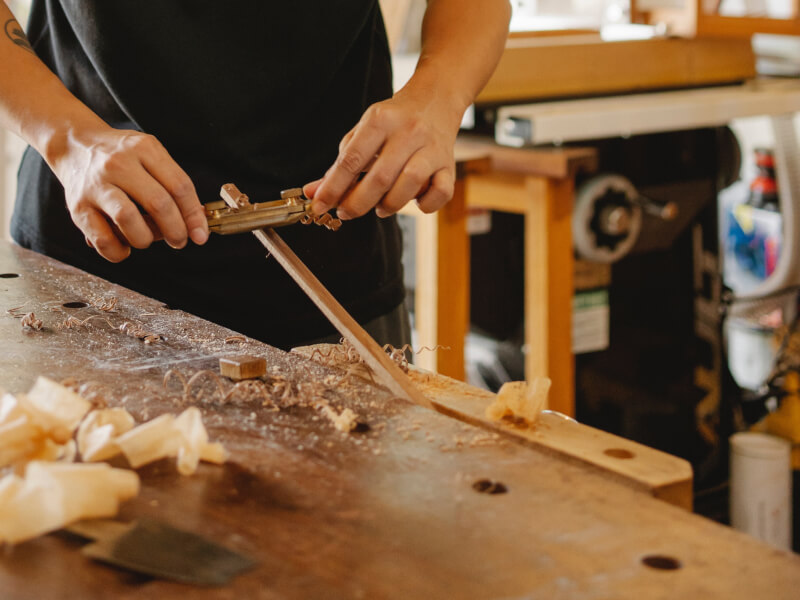 A person is using a hand tool for wood shaving.