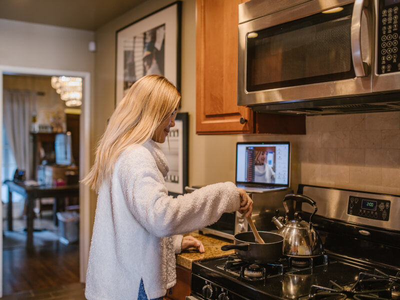 Woman cooking along with an online cooking class. 