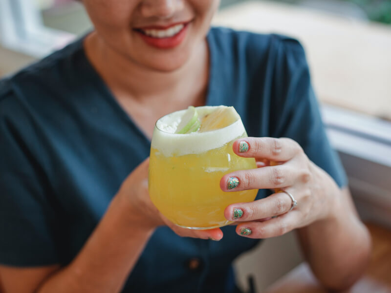 Woman smiling holding orange cocktail.