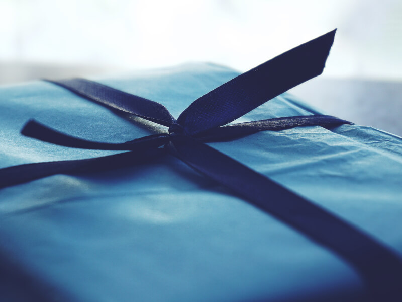 The top of a neatly wrapped present, finished with a dark blue ribbon.
