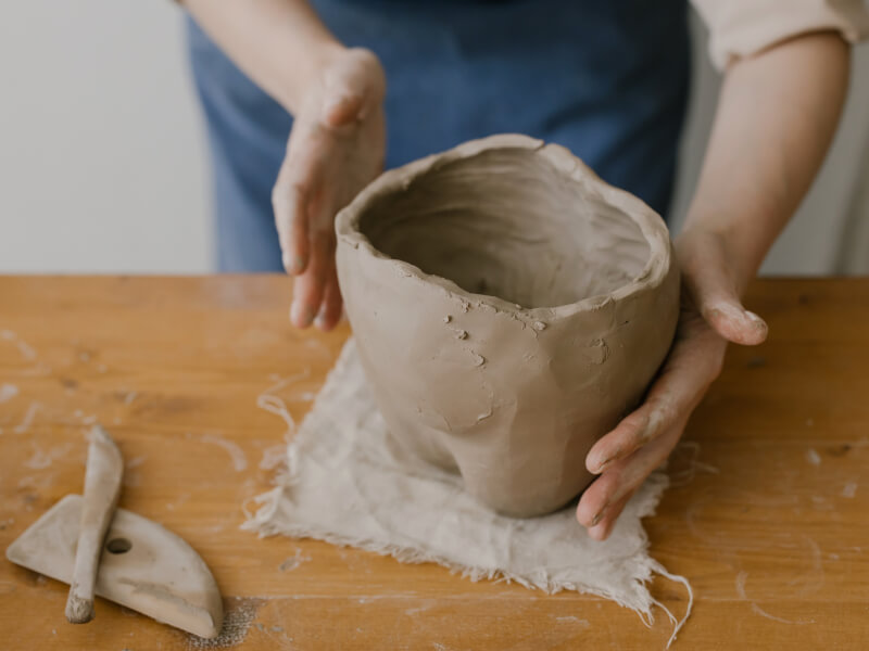 A person sculpting clay as they take part in a pottery at home class