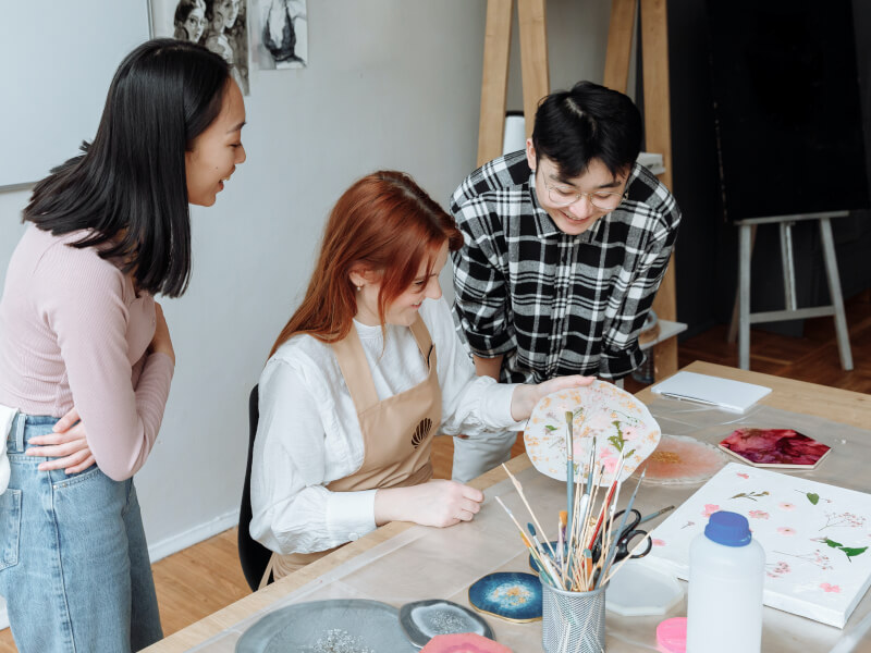 Three people at a vegan craft class making plant-based resin art.