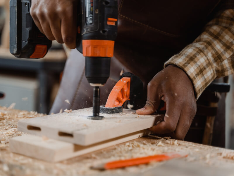 A person uses an electric drill when making a wood project.