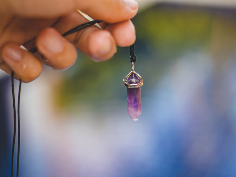 Homemade amethyst crystal pendant necklace attached to black string.