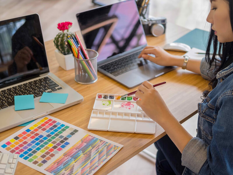 A person mixing watercolour paints at a desk
