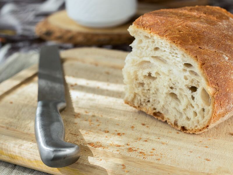 A load of handmade bread on a cutting board with a knife.