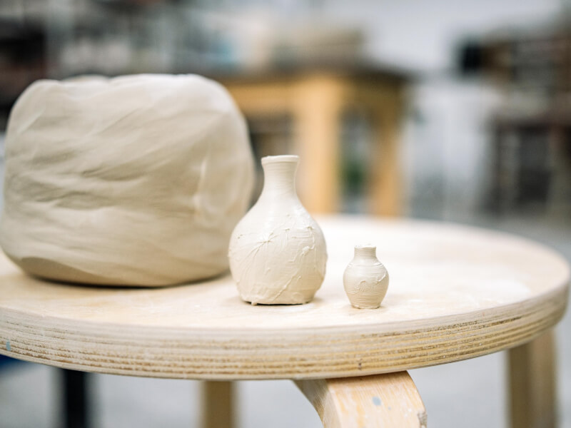 A selection of unglazed handmade pottery sits on a shelf