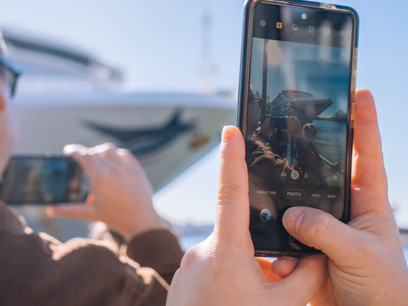 A close up of a person taking a picture of a boat at a smartphone photography class