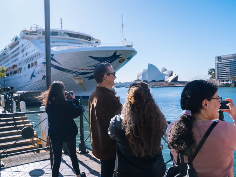 A group of people are taking pictures of a boat in a harbour at an iPhone photography class