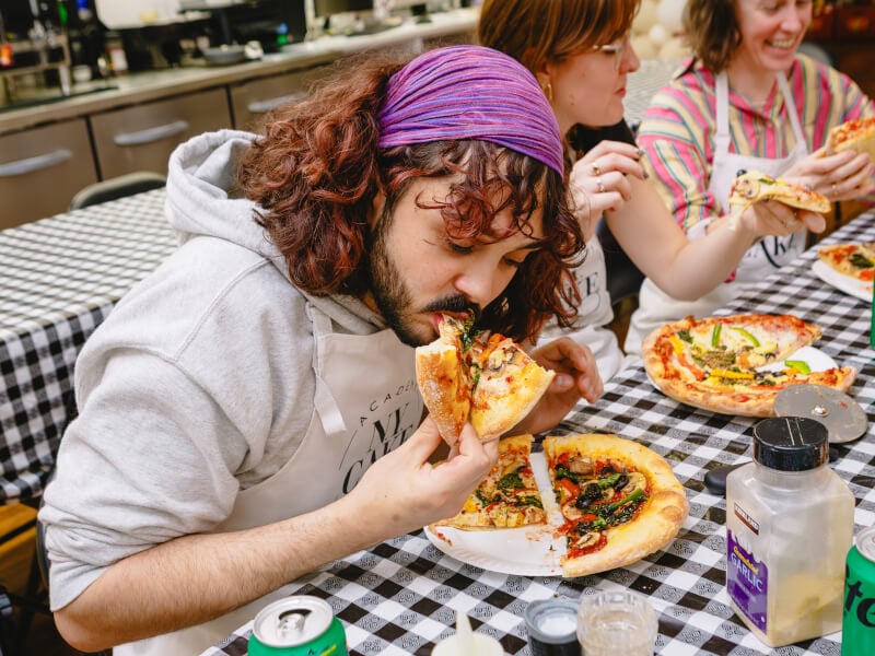 Person eating pizza in a pizza making class