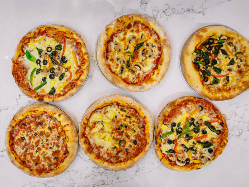 A selection of finished pizzas with different toppings from a cooking class