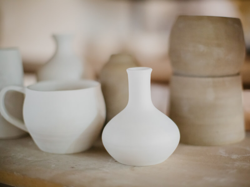A selection of clay pots in neutral colours sitting on a shelf
