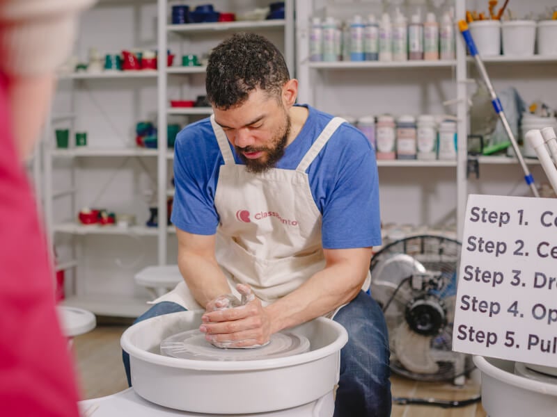 Man using a pottery wheel in a ceramics class