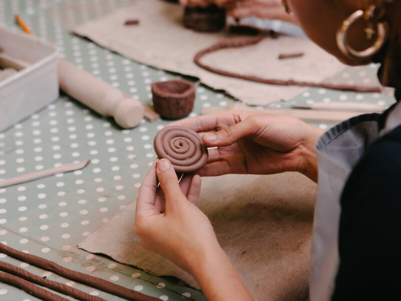 A close up of two hands coiling a piece of clay at a handbuilding pottery class