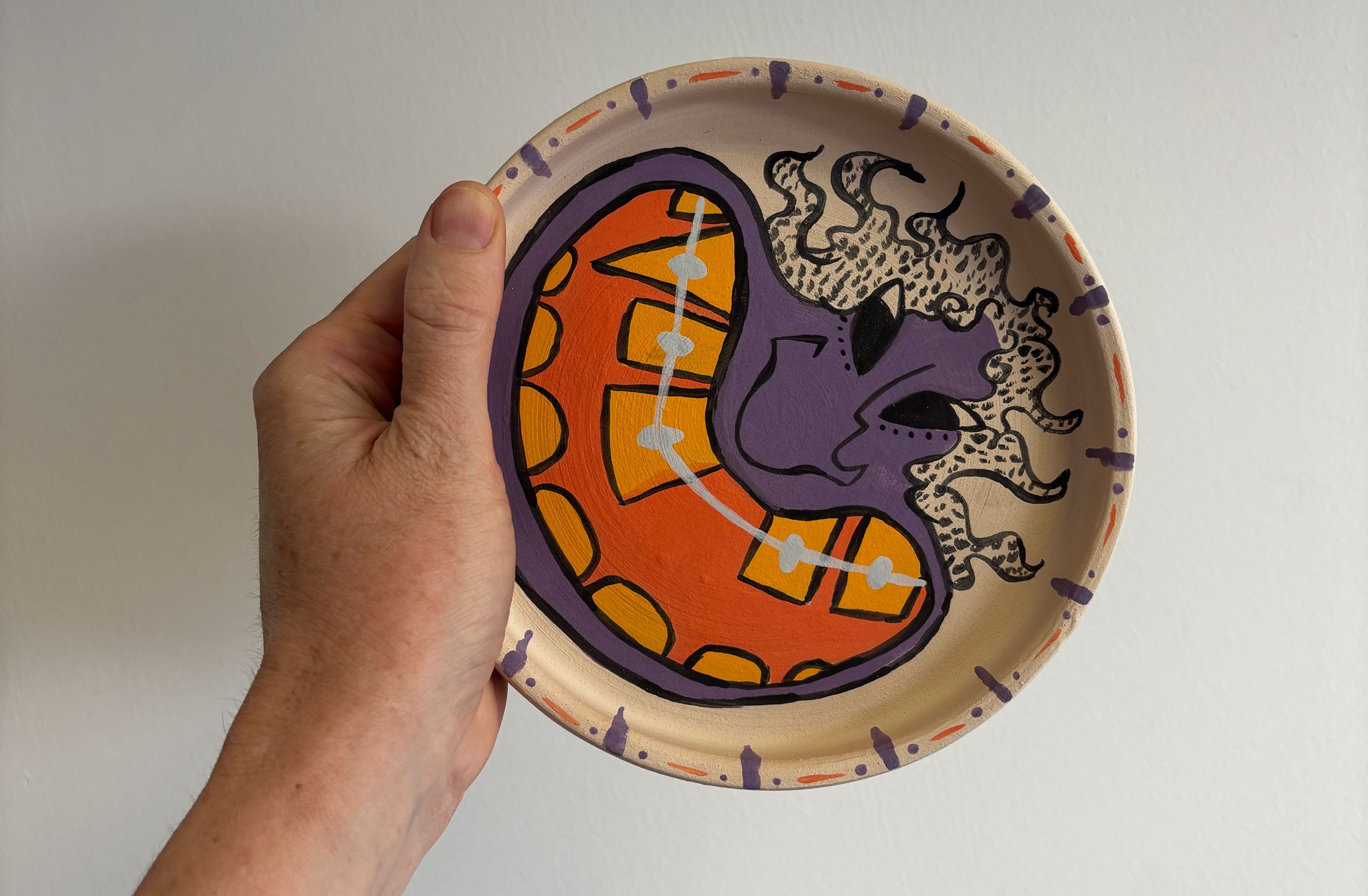 A hand holding a ceramic plate with a cartoon character