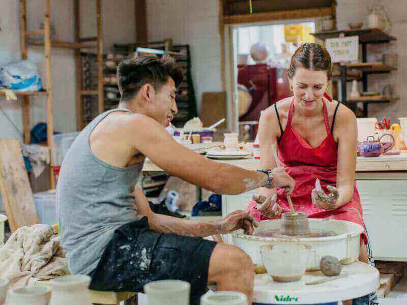 Couple using a pottery wheel in a pottery class