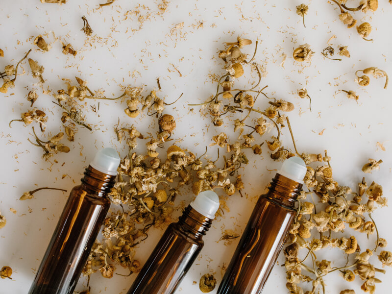Three bottles of DIY perfume next to some dried flowers.