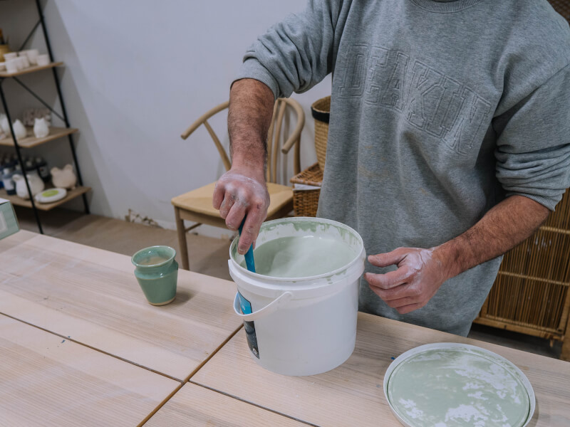 Person mixing potter's clay in a plastic tub