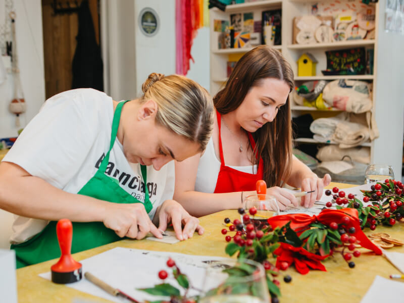 Two women making prints in a Christmas printmaking class