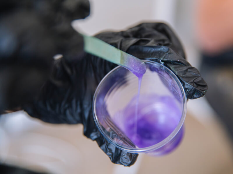 A close up of a person mixing purple paint at a fluid art class