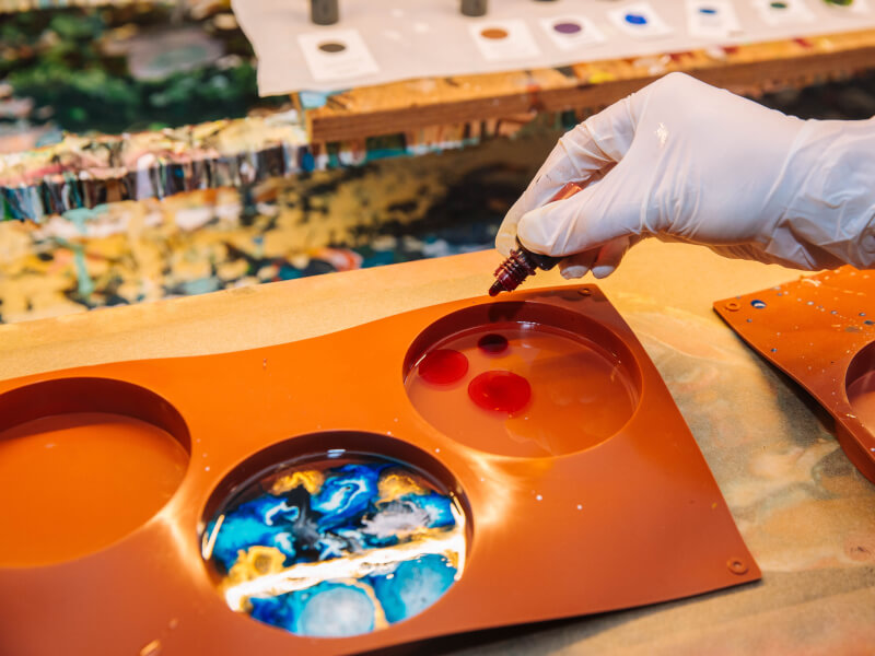 A person mixing colours in a tray at a resin class