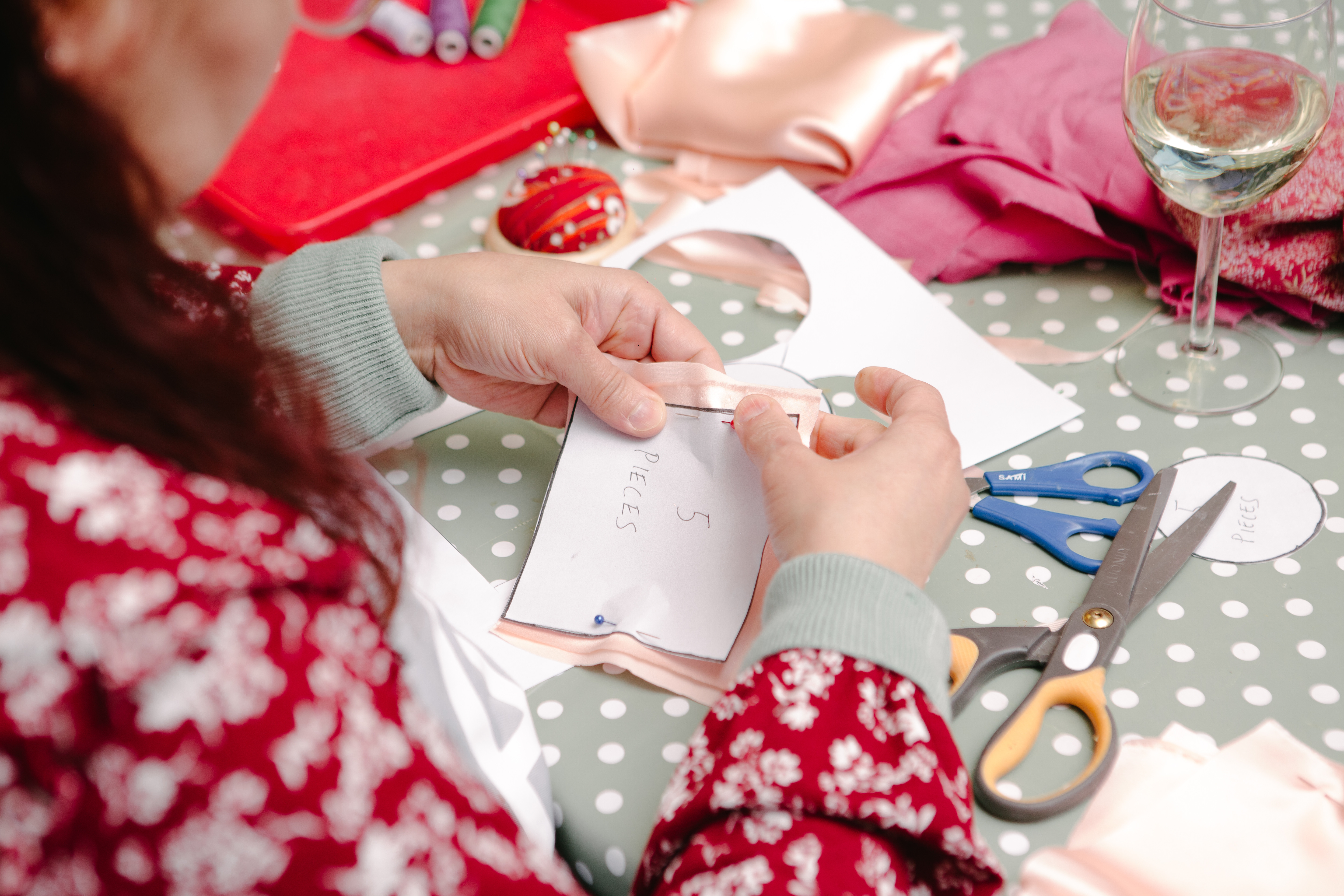 A close up of a person pinning a paper pattern to a piece of fabric